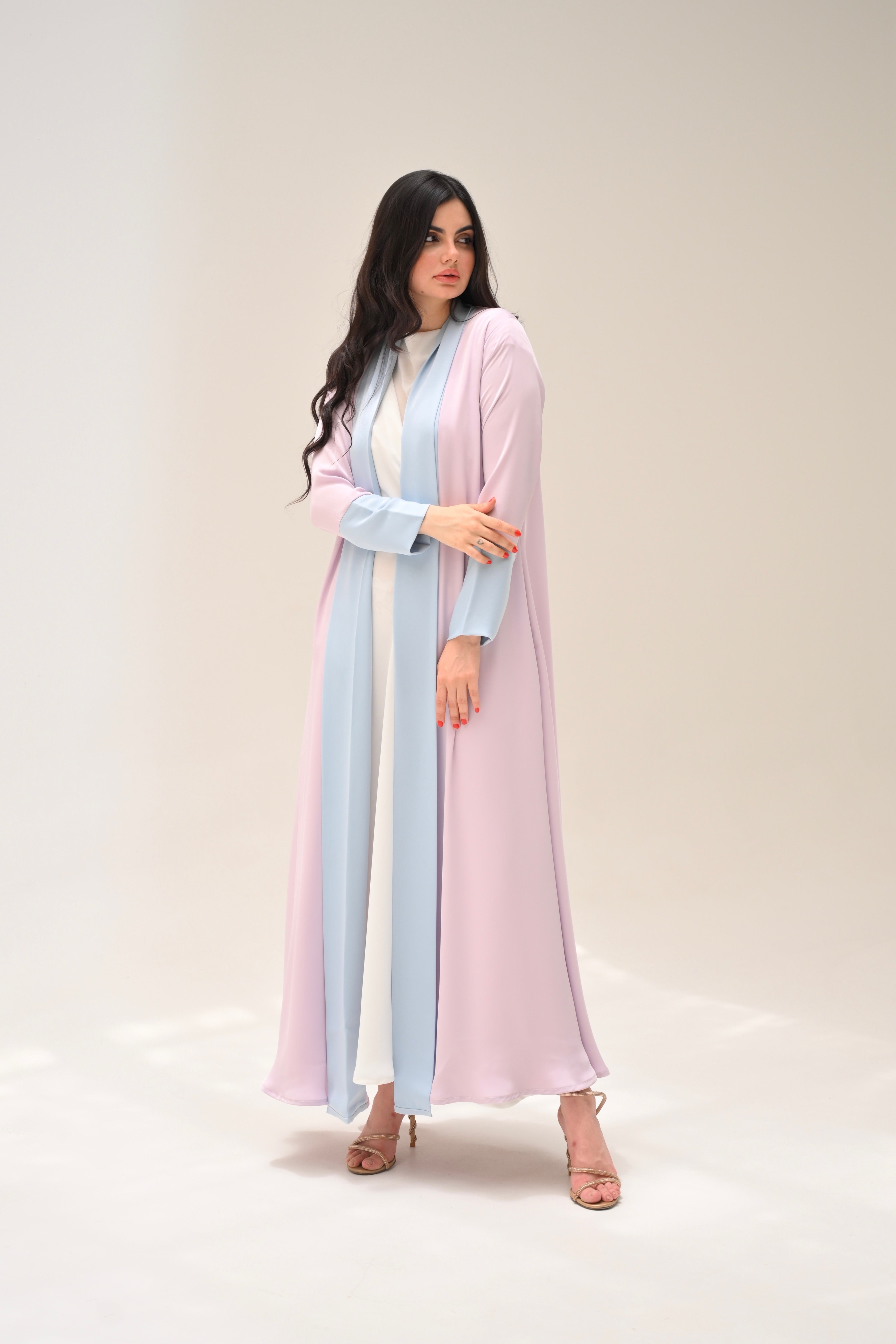 Woman wearing a pastel pink and light blue dress against a white background