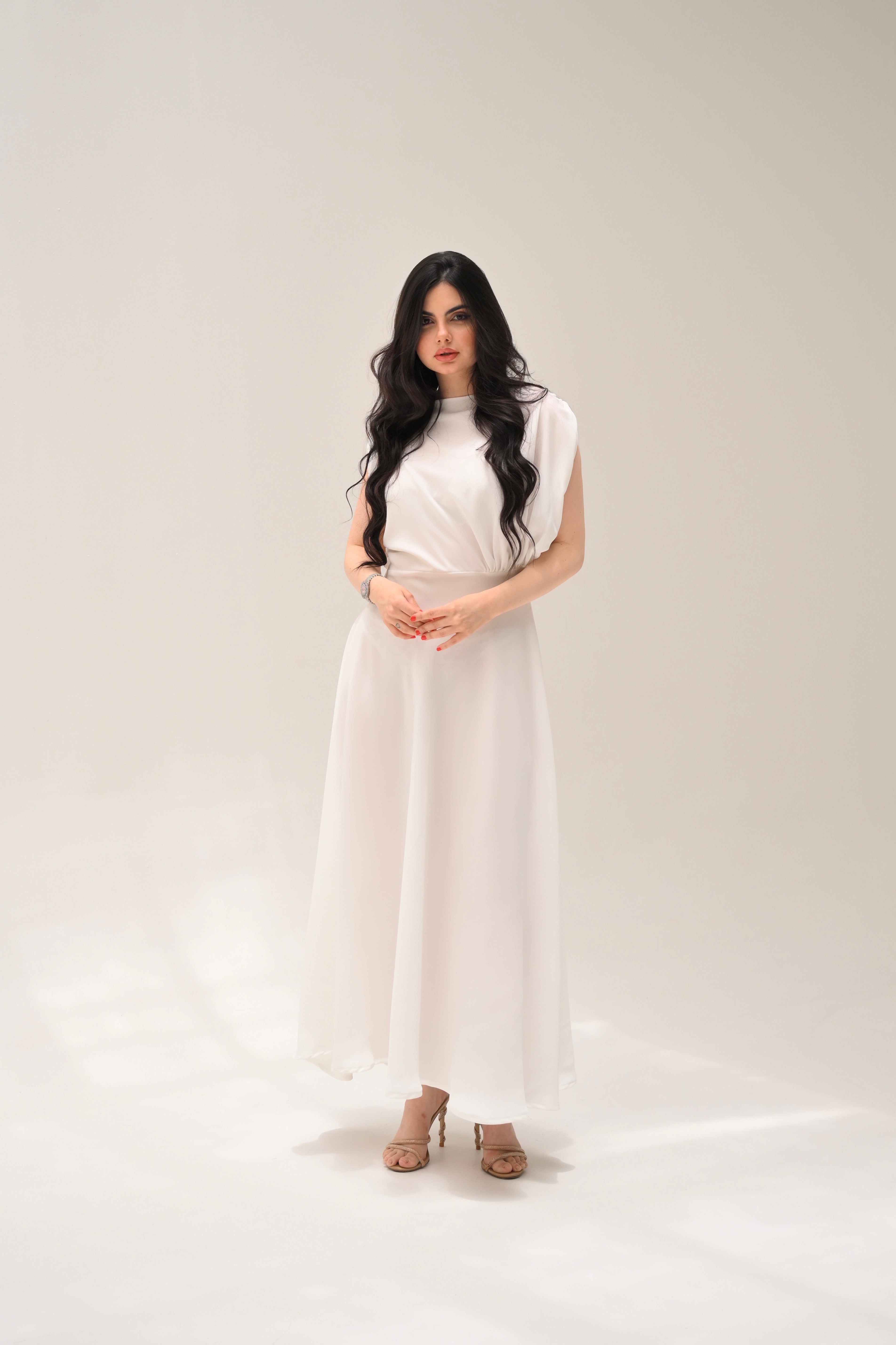 Woman wearing a white dress standing against a plain background