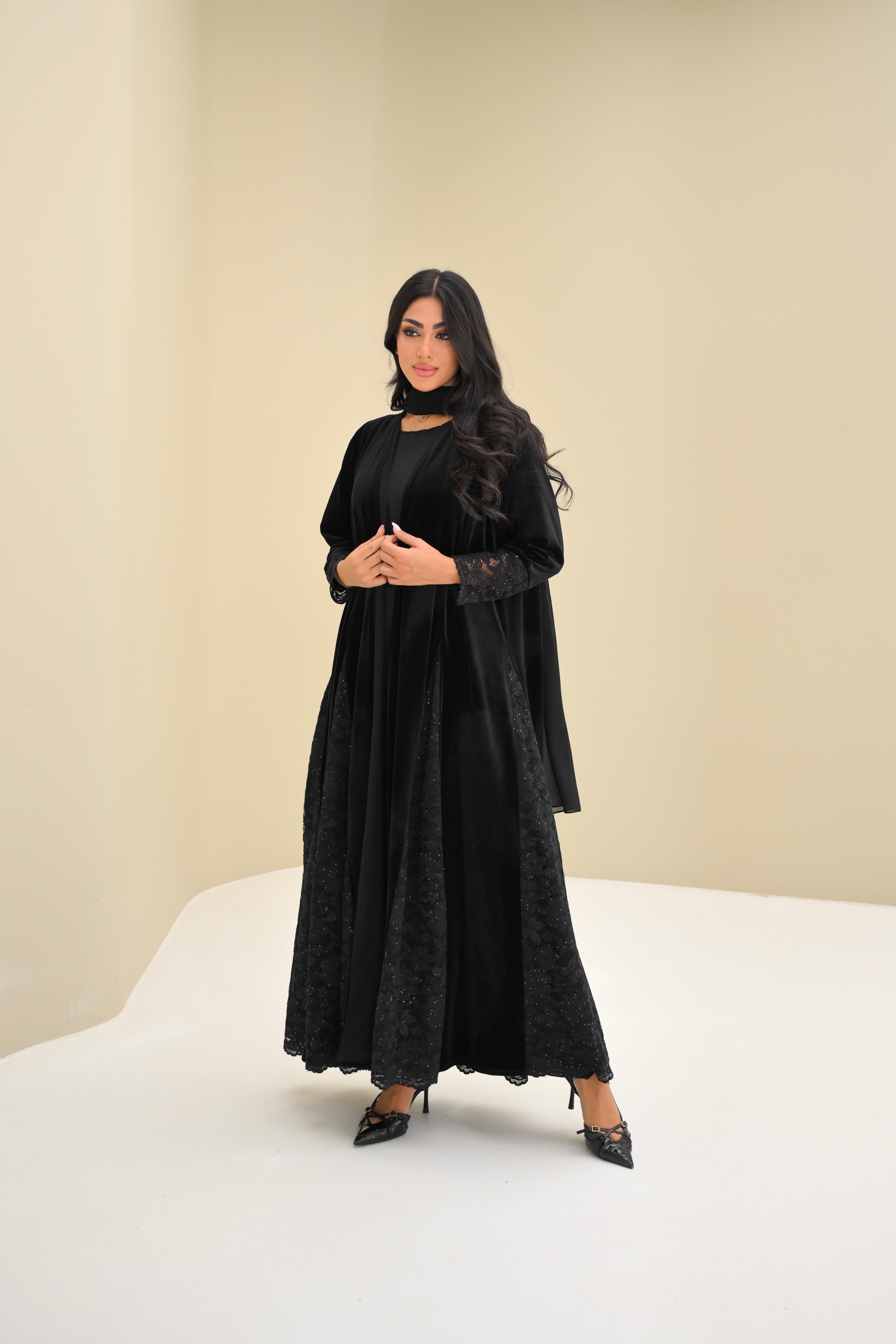 Woman wearing a black dress and cardigan on a white background