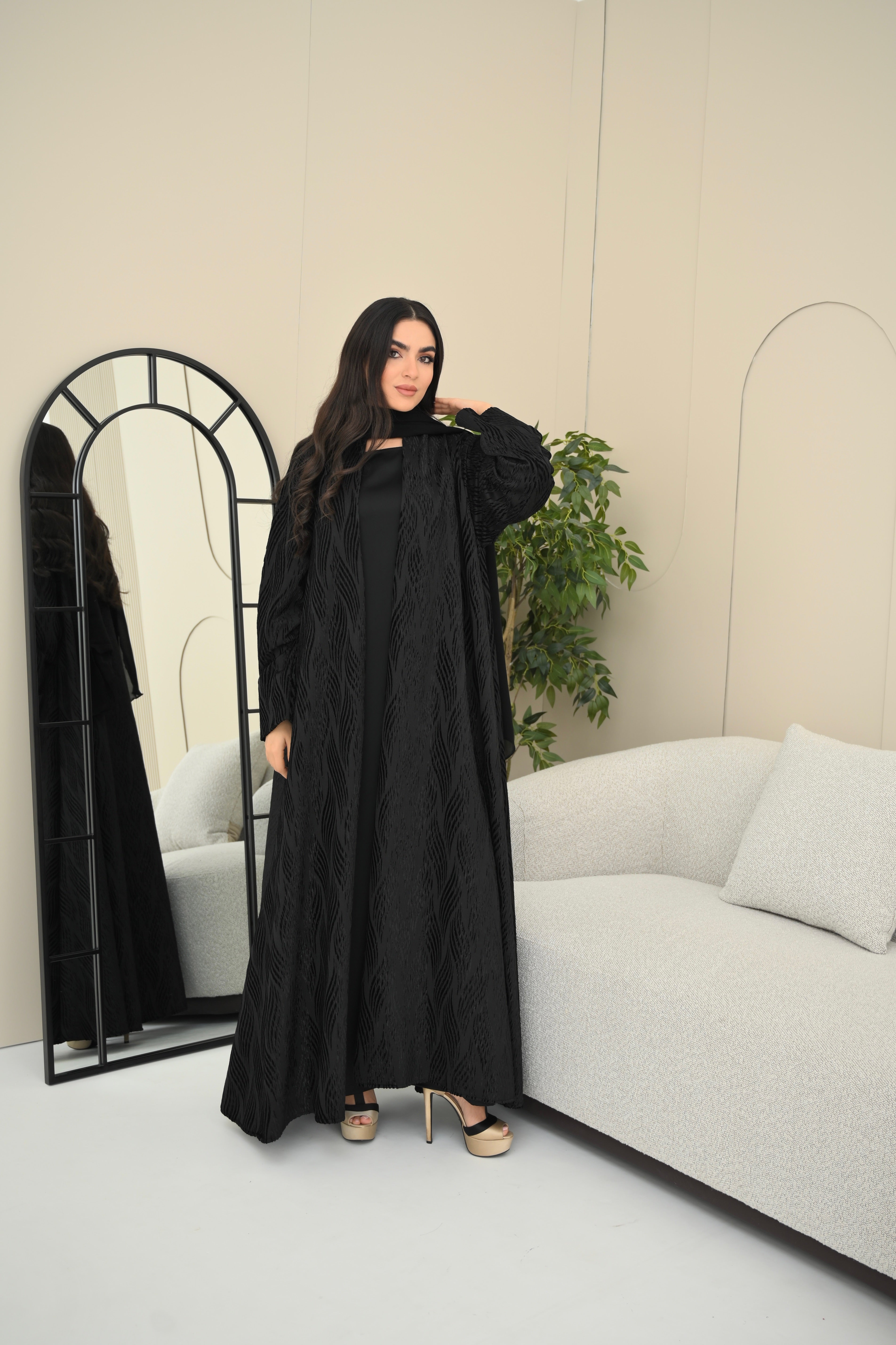 Woman in a black abaya standing in a modern living room.
