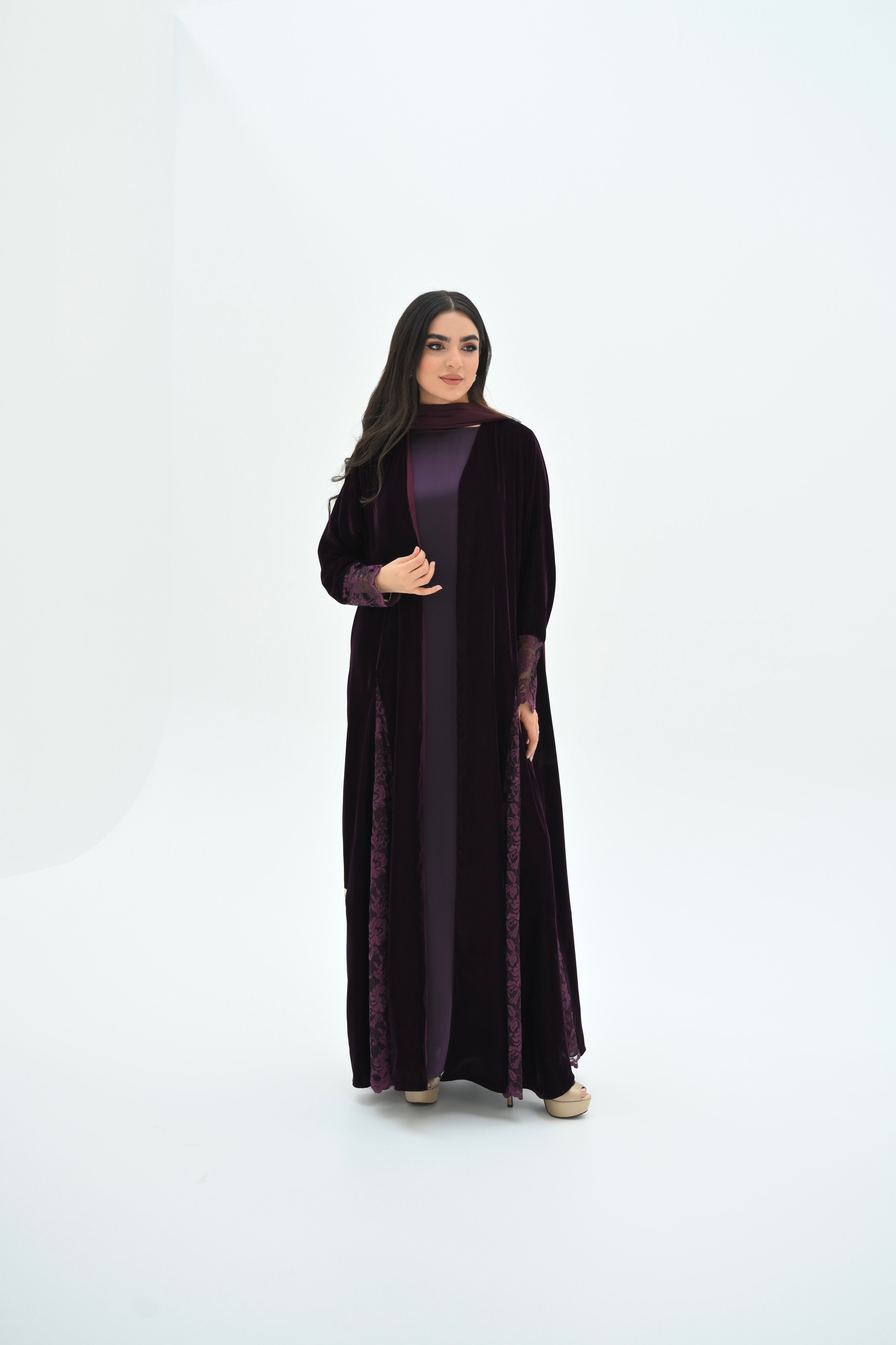 Woman wearing a long black dress with a textured pattern on a white background