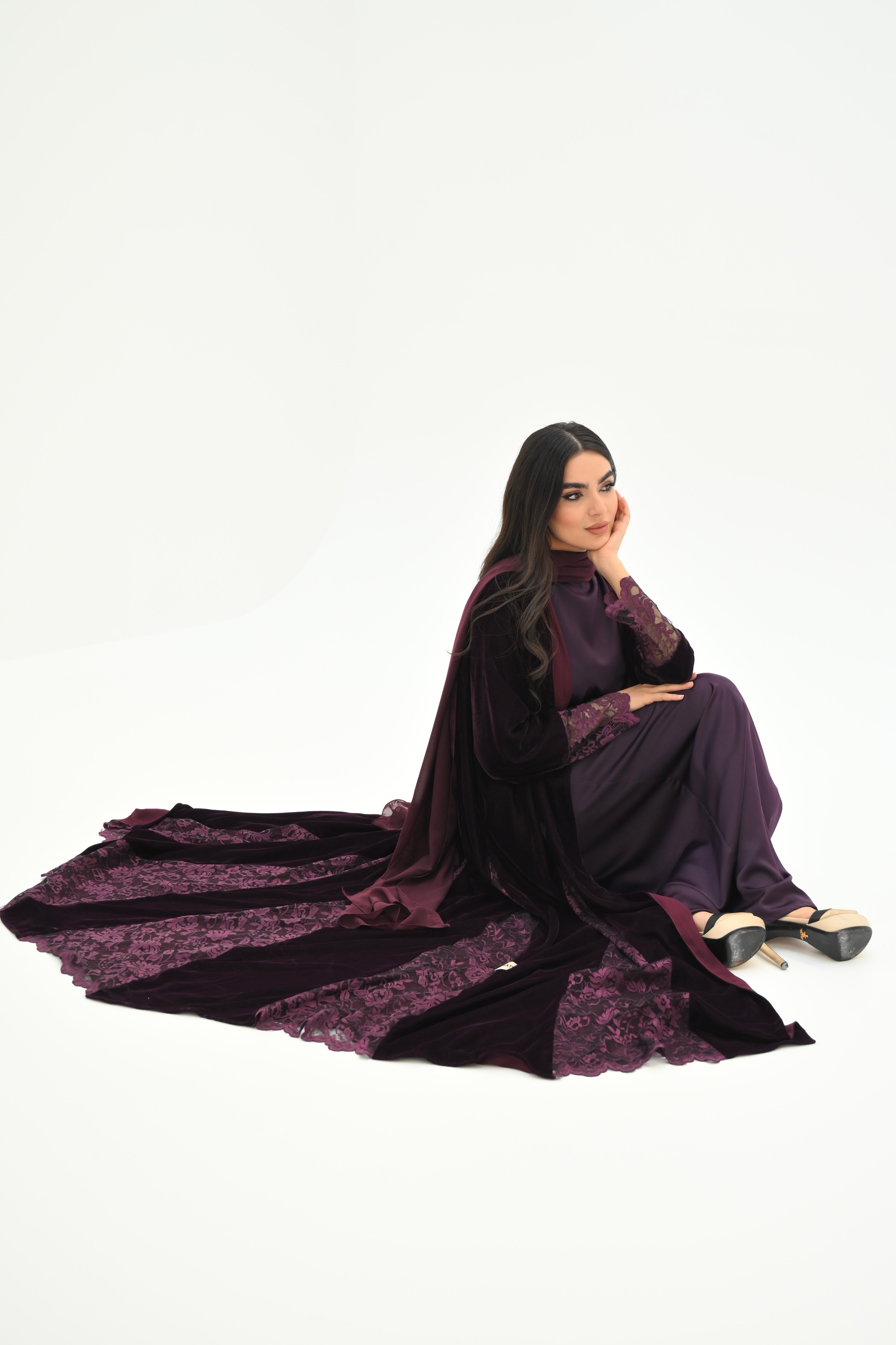 Woman wearing a long, dark purple dress with floral patterns on a white background