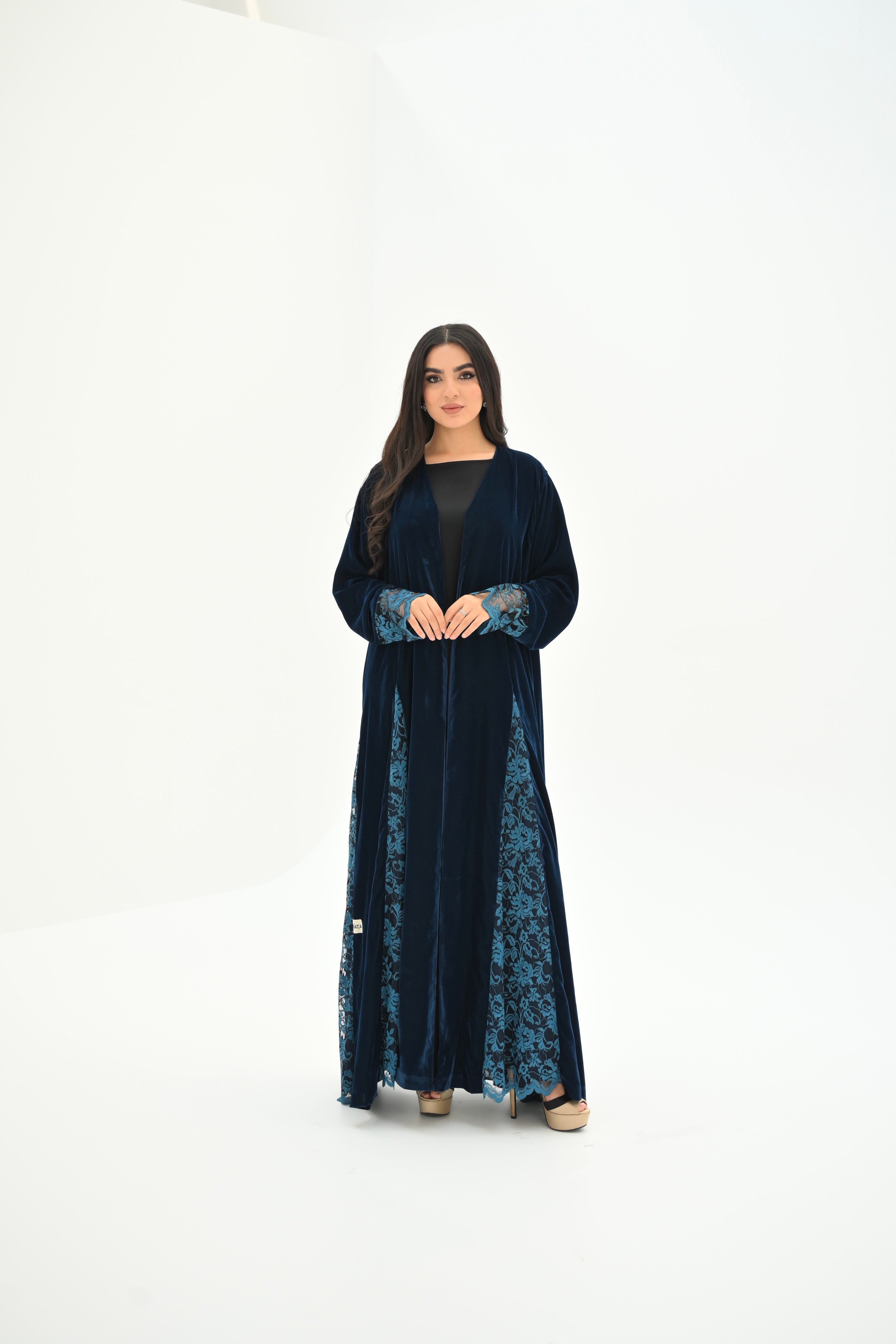 Woman wearing a long black dress with blue lace details on a white background