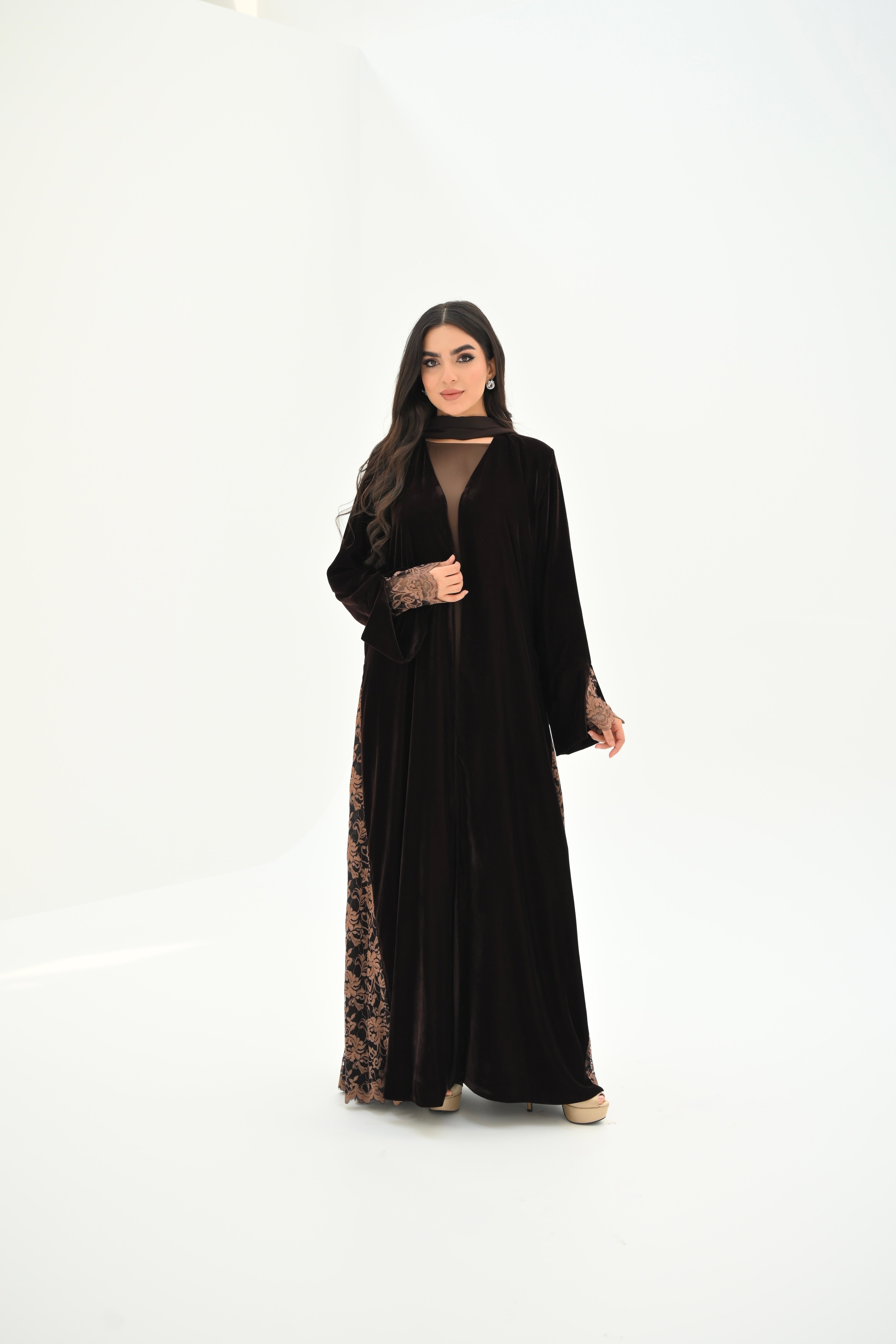 Woman wearing a black abaya with floral patterns on a white background