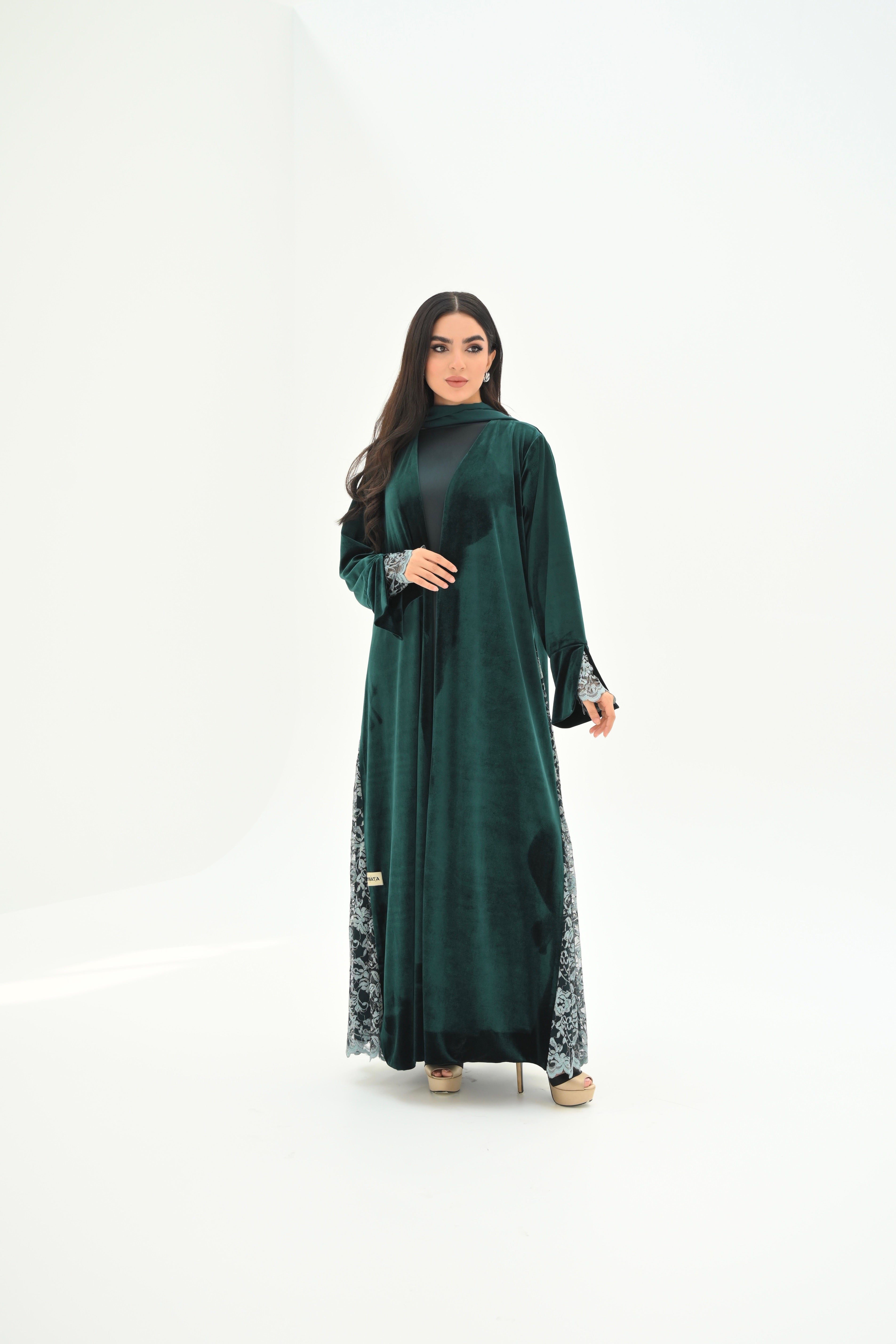 Woman wearing a green abaya with floral patterns on a white background