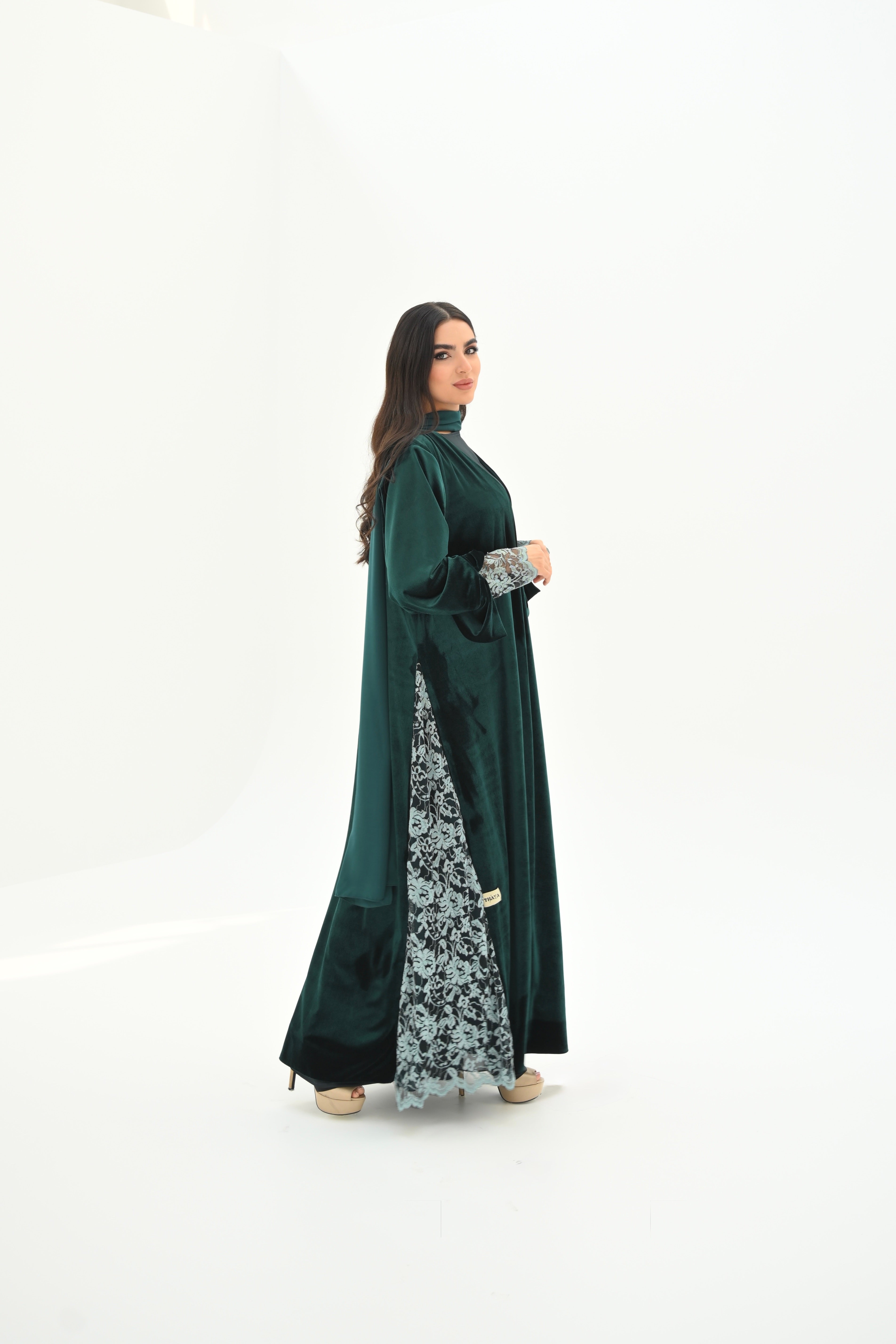 Woman wearing a long dark green dress with a floral patterned bottom half on a white background