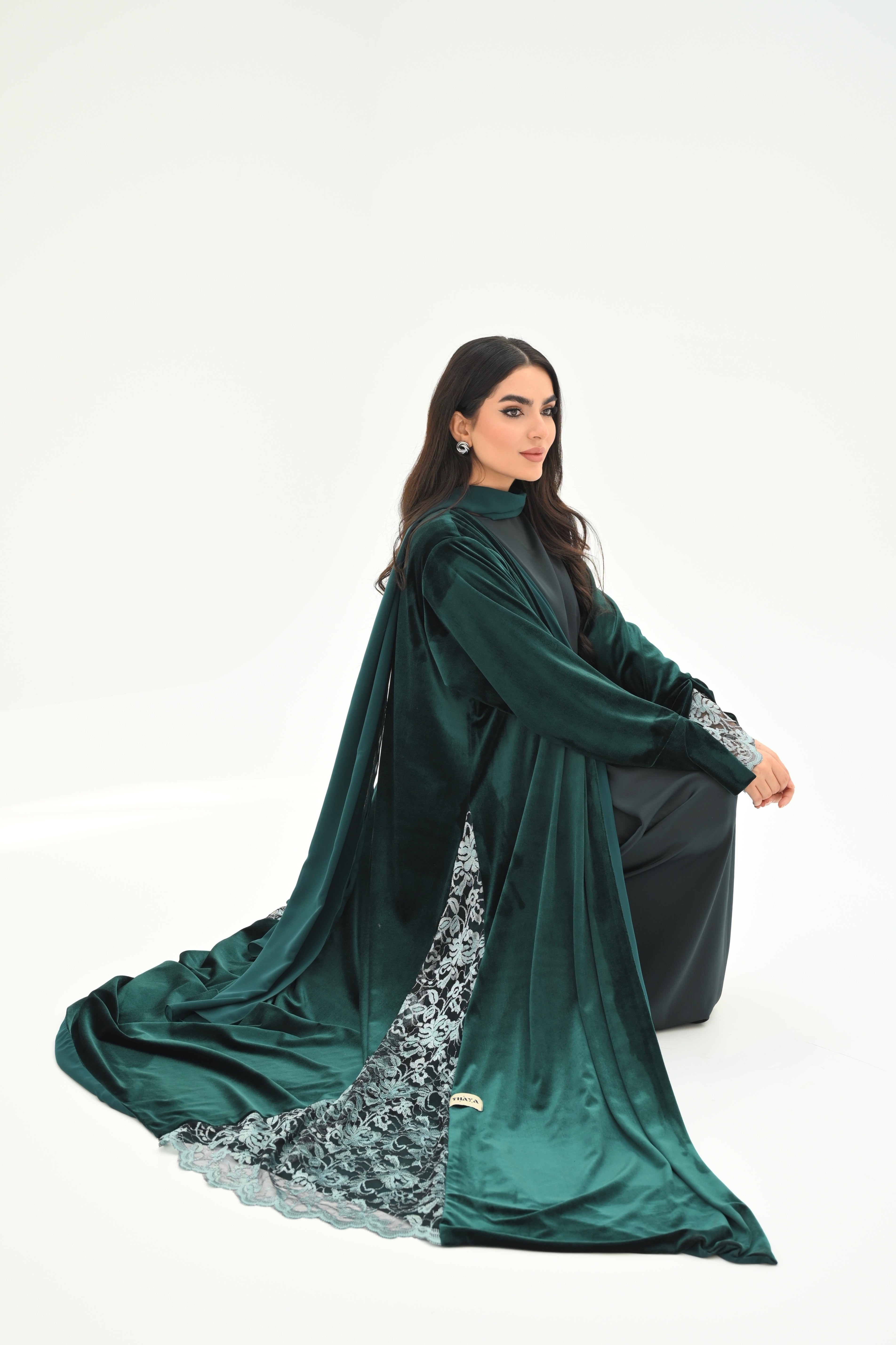 Woman wearing a green abaya with floral patterns on a white background