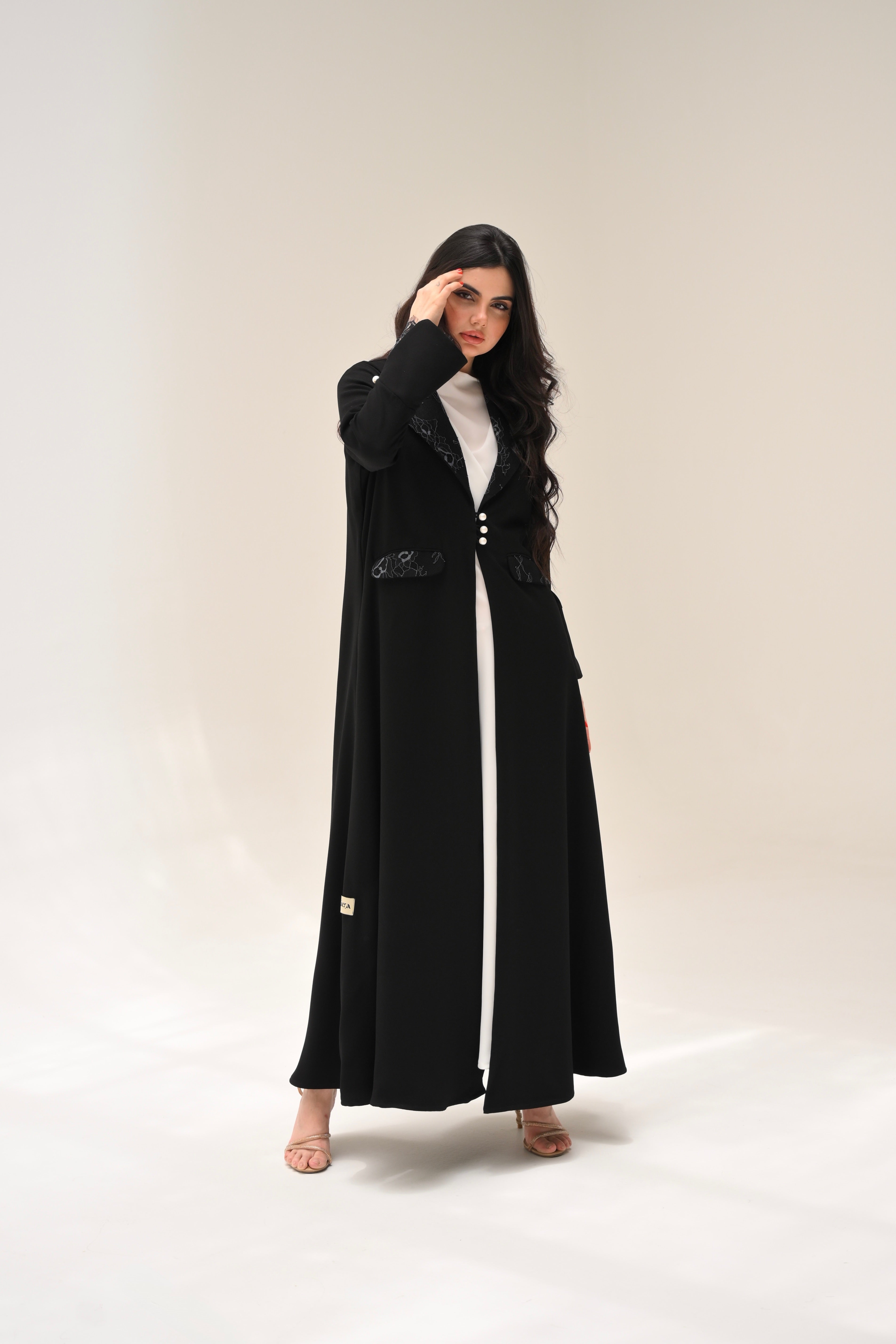 Woman wearing a long black coat on a plain background